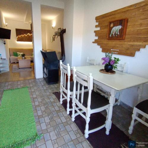 una cocina con mesa blanca y sillas y una habitación en Apartmani ZELENI MEDA en Mitrovac