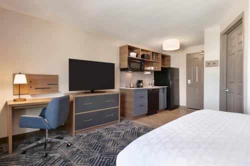 a bedroom with a bed and a desk with a television at Candlewood Suites Aberdeen-Bel Air by IHG in Riverside