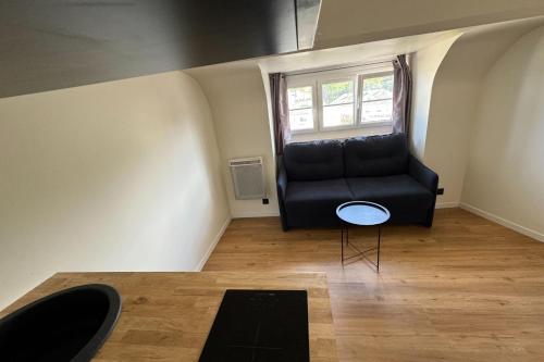 un canapé noir dans une pièce avec une fenêtre dans l'établissement Comfortable 16 m love nest in Caen, à Caen