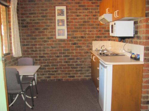 eine Küche mit einem Tisch und einer Ziegelwand in der Unterkunft Barham Colonial Motel in Barham