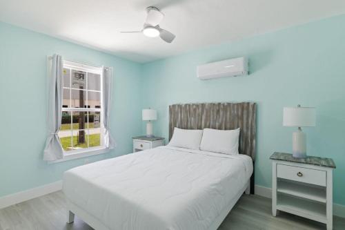 a blue bedroom with a white bed and a window at Superb Bonita Springs Residence Near Downtown in Bonita Springs