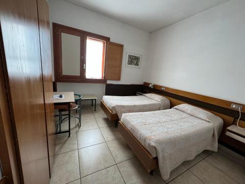 a room with two beds and a table and a window at Hotel Holidays in Roccaraso
