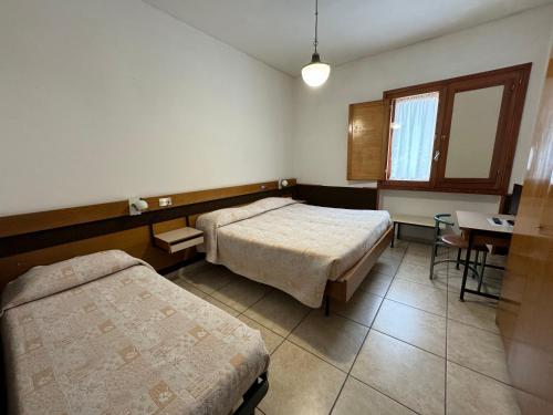 a room with two beds and a table and a window at Hotel Holidays in Roccaraso