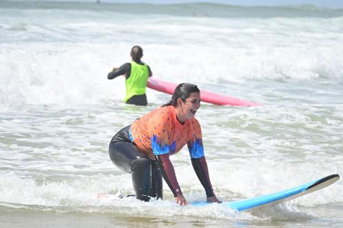 una mujer montando una ola en una tabla de surf en el océano en Lisbon Soul Surf Camp, en Cascais