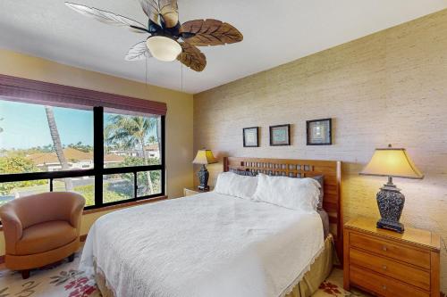 a bedroom with a bed and a chair and a window at Shores at Waikoloa #323 in Waikoloa