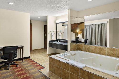 Habitación de hotel con bañera y escritorio. en Best Western Lakewood Inn, en Hebron
