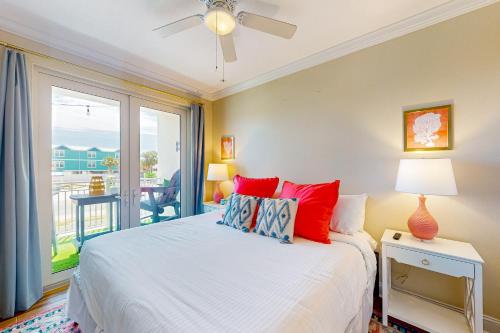 Un dormitorio con una cama con almohadas rojas y una ventana. en Tranquil Harbour 103: Casa Del Mar, en Mexico Beach