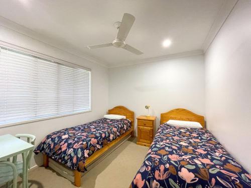 a bedroom with two beds and a ceiling fan at Seahaven - Toogoom in Toogoom