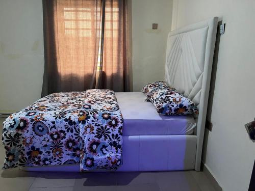 1 Schlafzimmer mit einem Bett mit Blumendecke in der Unterkunft YP-Made Luxurious 1 & 2 Bedroom Apartments in Eluju