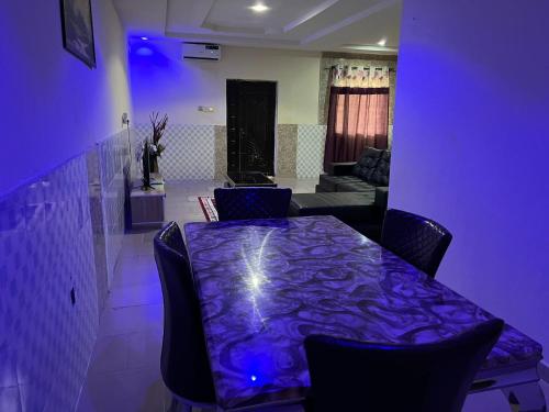 Habitación púrpura con mesa con sillas y sofá en YP-Made Luxurious 1 & 2 Bedroom Apartments en Eluju