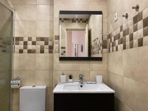 Un baño con lavabo, inodoro y espejo. en Apartamentos Benal Beach Group, en Benalmádena
