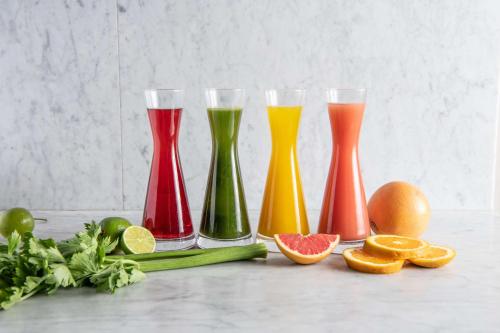 four colorful vases sitting on a table with fruits and vegetables at One&Only Cape Town in Cape Town