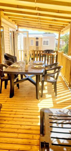 a patio with a table and chairs on a deck at Mobil-home Le cocon FUN PASS NON INCLUS in Canet-en-Roussillon