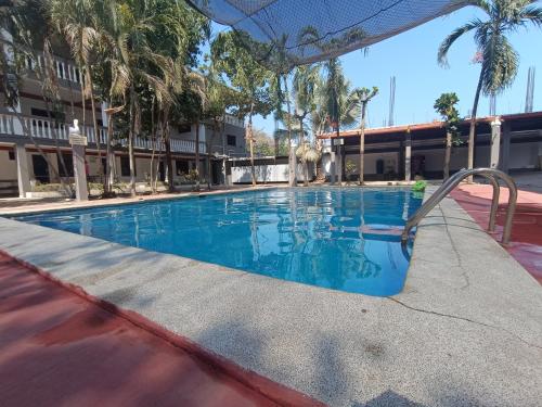 une piscine dans un hôtel avec des palmiers dans l'établissement 25. Olas y Mar, à La Libertad