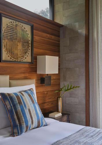 a bedroom with a bed and a lamp on a wall at One&Only Gorilla's Nest in Kinigi