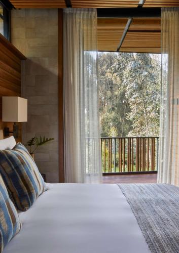a bedroom with a bed and a large window at One&Only Gorilla's Nest in Kinigi