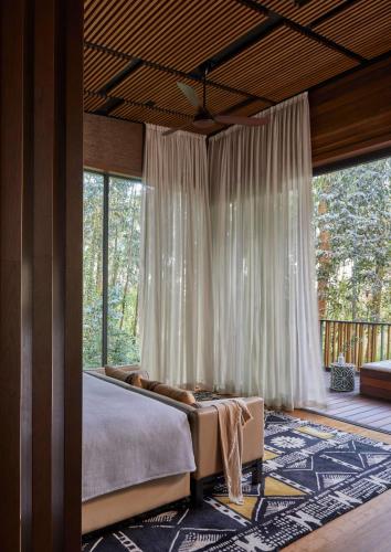 a bedroom with a bed and a large window at One&Only Gorilla's Nest in Kinigi