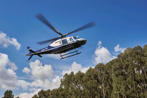 a helicopter flying in the sky over some trees at One&Only Gorilla's Nest in Kinigi