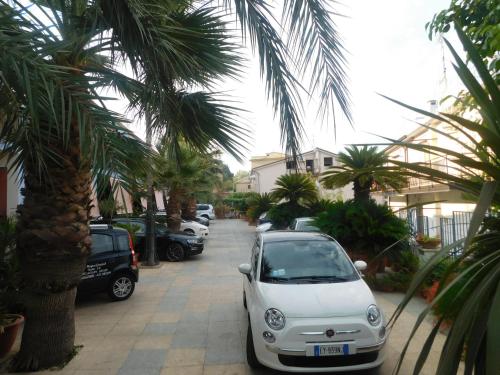 a white car parked on a street with palm trees at Hotel Blumentag in Paola