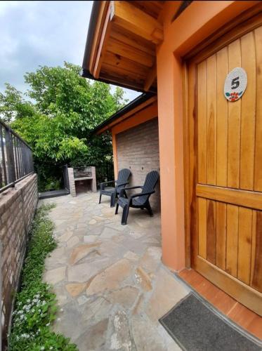 a patio with two chairs and a wooden door at Cabañas Bosque Andino con hidromasaje in Esquel