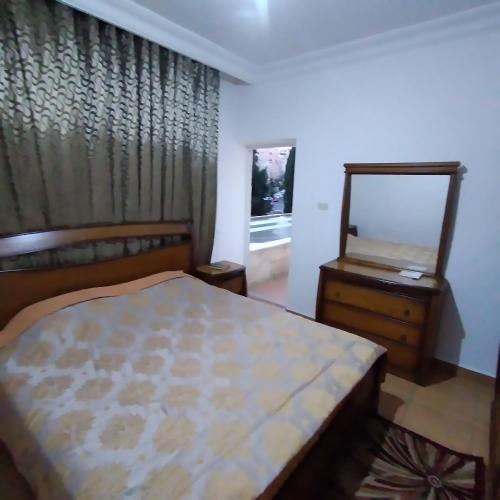 um quarto com uma cama, um espelho e uma cómoda em عمان الجاردنز خلف بن العميد em Amã