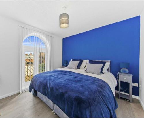 Stylish 2 bedroom Apartment in Kettering Town Centre, sleeps 4, free parking, wifi, Sky, Netflix في نورثامبتون: غرفة نوم زرقاء مع سرير بجدار ازرق