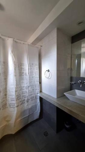 een badkamer met een douche, een wastafel en een spiegel bij Departamento dos ambientes. in Castelar