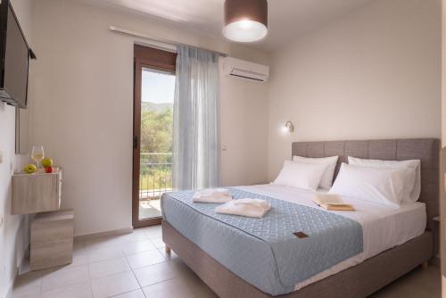 a bedroom with a large bed and a window at Tesoro luxury apartments in Sivota