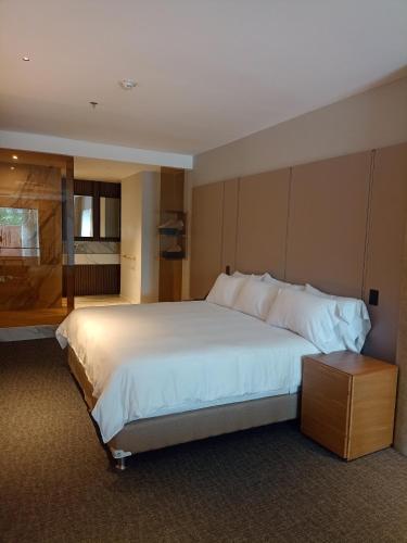 a bedroom with a large white bed and a window at Alko Hotel Integrado in Cali