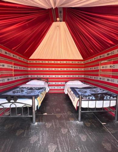 a room with two beds in a red room at Wadi Rum Heaven Camp in Wadi Rum
