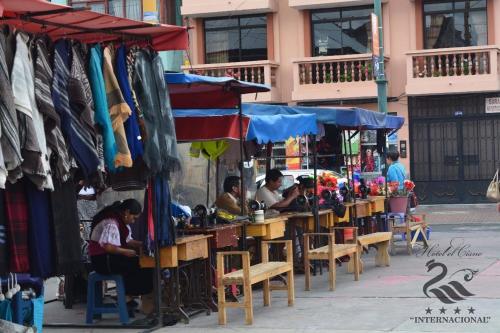 a group of people sitting at tables in an outdoor market at Hotel El Cisne Internacional in Riobamba