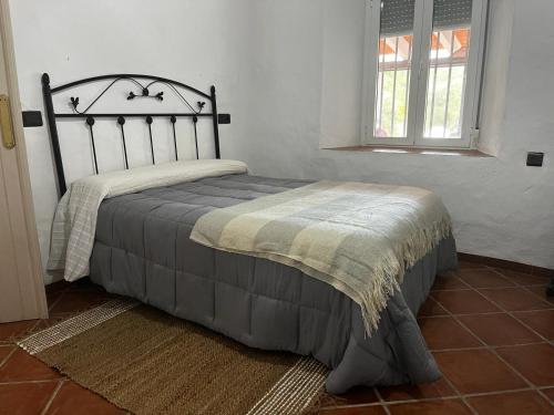 uma cama num quarto branco com uma colcha em Magnífica casa cerca del rio em Huelva