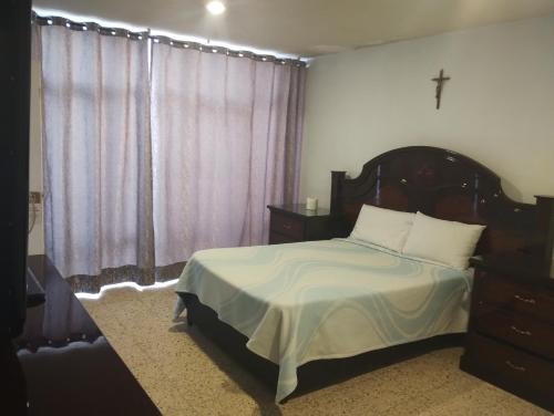 a bedroom with a bed and a cross on the wall at PROVENZA HOTEL & SUiTES in Atlixco