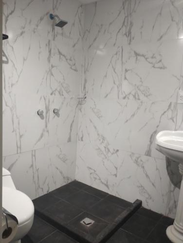 a white bathroom with a toilet and a sink at PROVENZA HOTEL & SUiTES in Atlixco