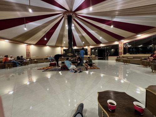 Desert heart camp في وادي رم: مجموعة من الناس يجلسون على الأرض في غرفة كبيرة