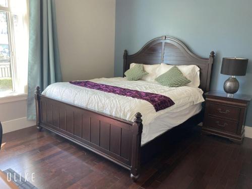uma cama com cabeceira em madeira e almofadas em Comfortable suite for guests to use independently em Burnaby