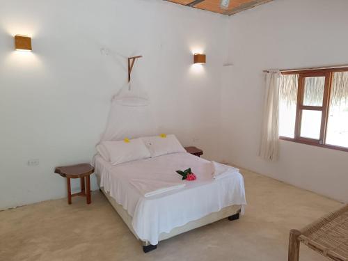 Un dormitorio con una cama blanca con una flor. en Sierra Sagrada Tayrona en Guachaca