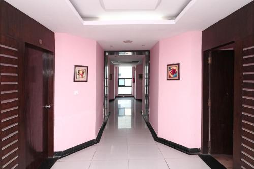 korytarzem w budynku z różowymi ścianami w obiekcie SPOT ON Hotel Center Point w mieście Rāmpura