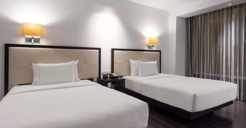 two beds in a hotel room with white sheets at Hilton DoubleTree Guadalajara Centro Historico in Guadalajara