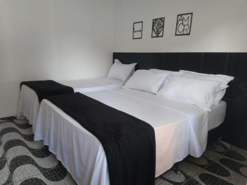 two beds in a room with white sheets and pillows at Pousada Costa Mar in Rio das Ostras