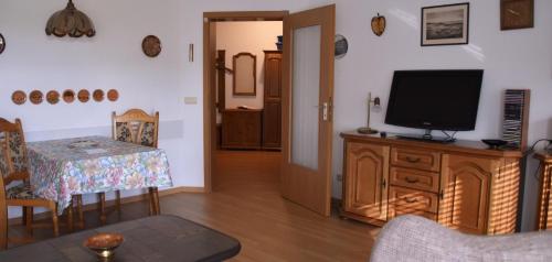 soggiorno con TV e mobile in legno con tavolo di Ferienwohnung Rodachtalblick 927 a Bad Rodach