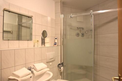ein Bad mit einer Dusche, einem Waschbecken und einem Spiegel in der Unterkunft Ferienwohnung Rodachtalblick 927 in Bad Rodach