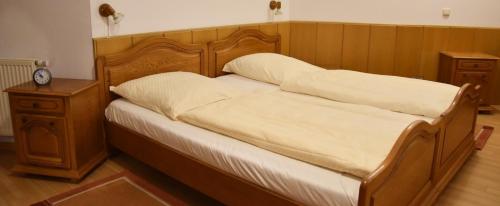 Bett mit weißer Bettwäsche und einem Kopfteil aus Holz in der Unterkunft Ferienwohnung Rodachtalblick 927 in Bad Rodach