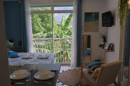 a living room with a table and a large window at * LE DAUPHIN * Vue mer, clim et parking in Le Marin