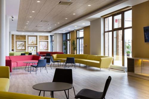a waiting room with yellow couches and tables and chairs at Family-Hotel in Balástya