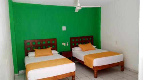 twee bedden in een kamer met een groene muur bij Casa Mexicana Barra de Navidad in Barra de Navidad