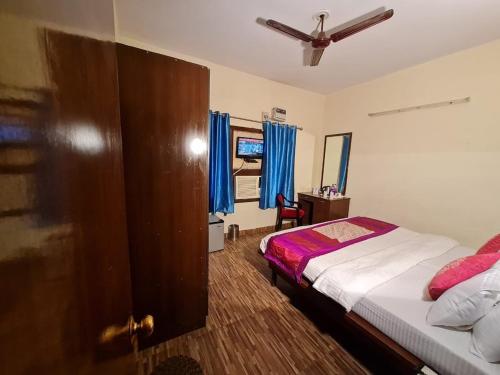 a bedroom with a bed and a window with blue curtains at Capital O 3695 Hotel Daichi in Dehradun