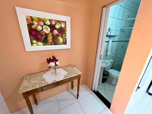 a bathroom with a table with a painting on the wall at Mar de Guarajuba in Guarajuba