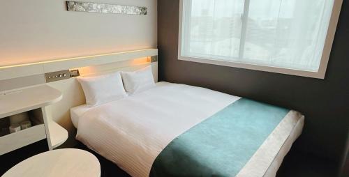 a bedroom with a bed and a desk and a window at Urban Hotel Kyoto Shijo Premium in Kyoto