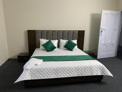 1 dormitorio con 1 cama grande con almohadas verdes en The Nook, en Muzaffarabad